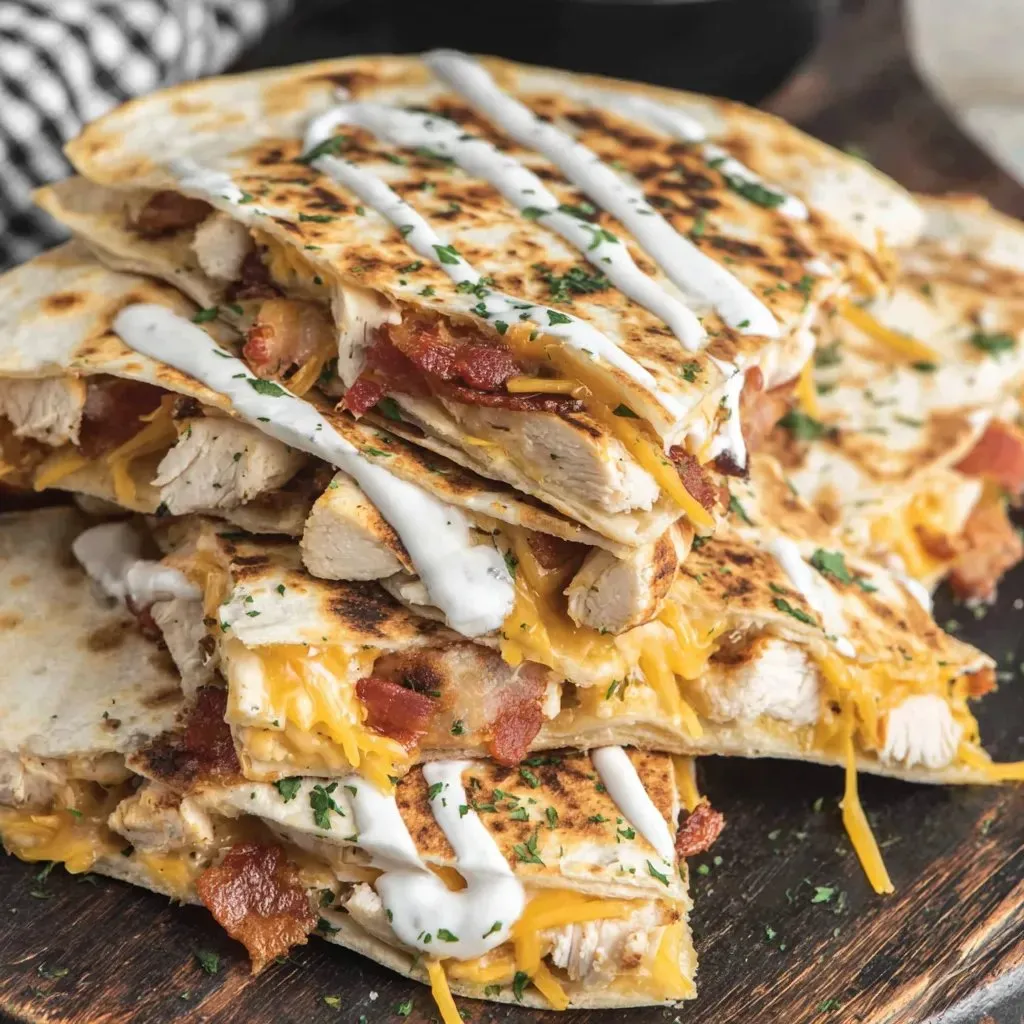 Stack of chicken sandwiches with bacon and cheese.