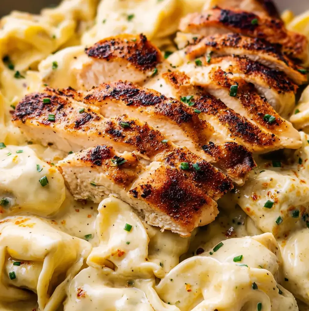 A plate of pasta with chicken on top.