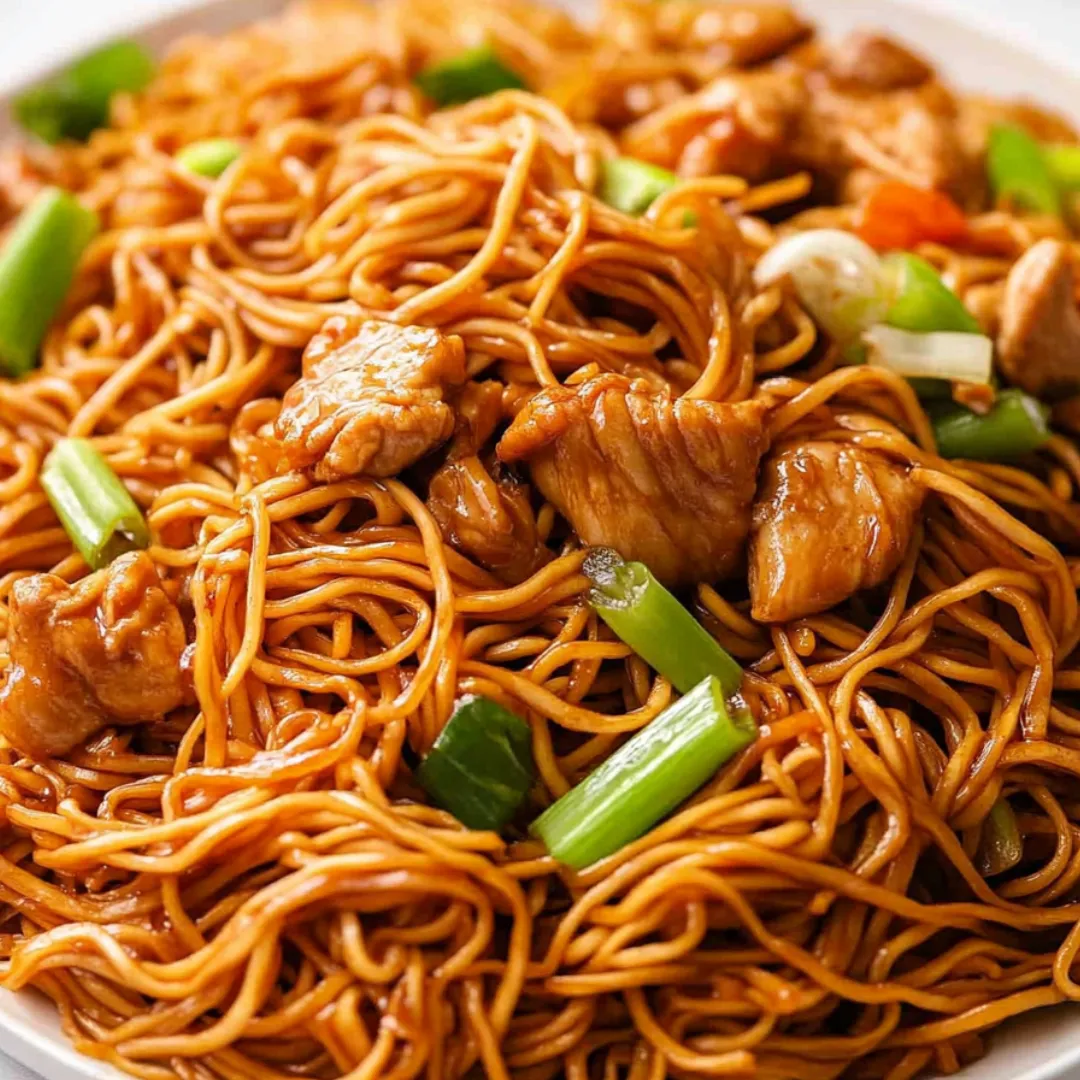 A plate of noodles with meat and vegetables.