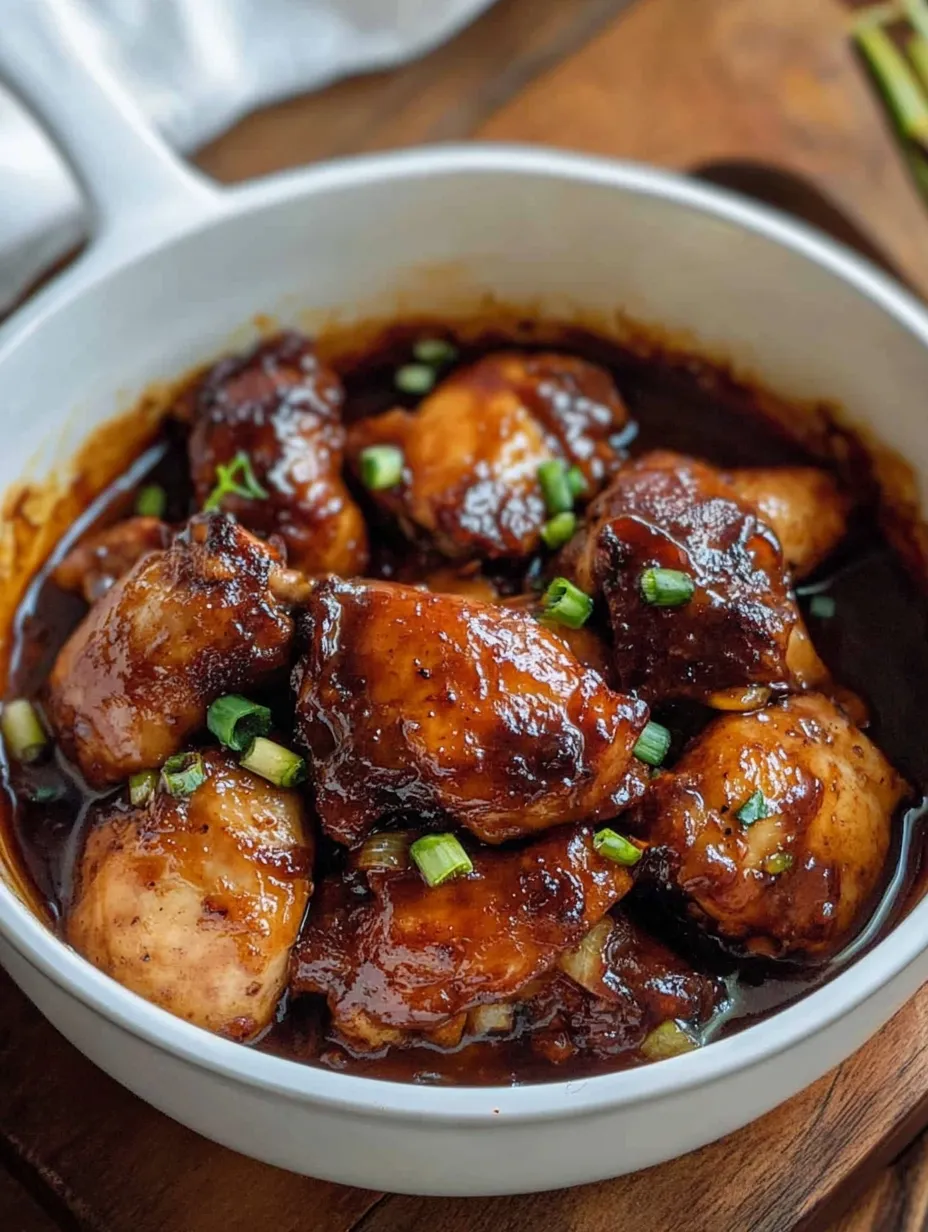 A bowl of chicken with a green garnish.
