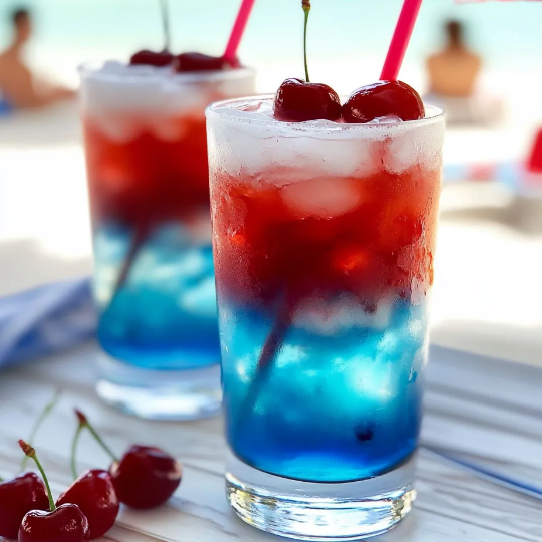 Two glasses filled with a colorful layered drink, cherries nearby.