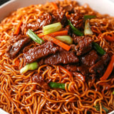 A bowl of noodles with meat and vegetables.