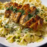 A plate of pasta with chicken and herbs.