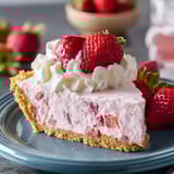 A slice of strawberry cheesecake with whipped cream.