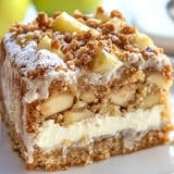 A slice of cake with white icing and apple slices.