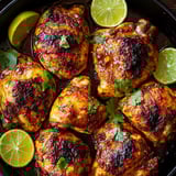 A bowl of chicken with limes and herbs.