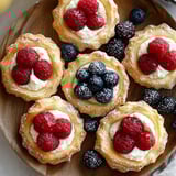 A plate of pastries with berries and cream.