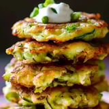 A stack of pancakes with zucchini and white sauce.
