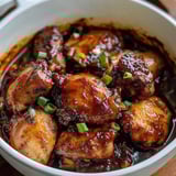 A bowl of food with chicken and sauce.