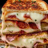 A stack of three grilled cheese sandwiches with pepperoni.