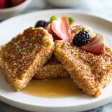 A plate of French toast with strawberries and blueberries.