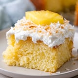 A slice of cake with white frosting and a pineapple slice on top.