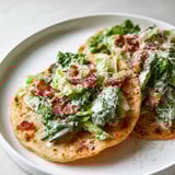 Chicken tacos, fresh greens, and bacon on a plate.