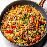 Heaping bowl with noodles, meat, and colorful veggies.