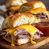 Cheesy beef sandwich sitting on a wooden board.