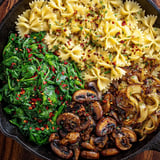 A pan filled with pasta, mushrooms, plus spinach.