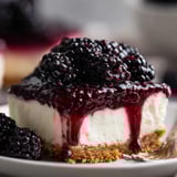 A slice of cheesecake topped with glossy blackberries.