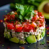 A dish loaded with avocado, tomato, and fresh cilantro.