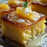 Slice of fluffy yellow cake topped with a green leaf on a white plate.