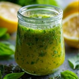 A glass filled with bright green dressing and a lemon slice.