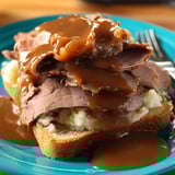 A plate loaded with juicy meat and gravy.