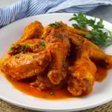 Saucy chicken wings arranged on a plate.