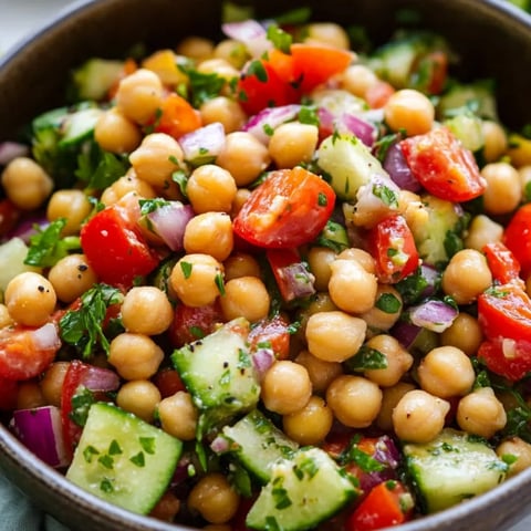 A bowl loaded with tomatoes, cucumbers, and chickpeas.